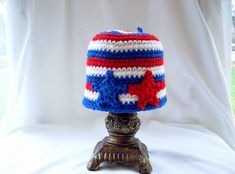 a red, white and blue crocheted hat sitting on top of a wooden stand