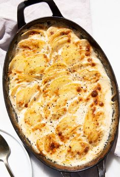 a skillet filled with food on top of a white cloth next to a spoon