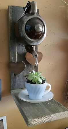 there is a cup and saucer on the table with a potted plant in it