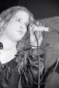 a woman holding a microphone up to her ear while standing in front of a microphone