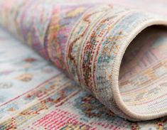 a close up view of a multi colored rug with a rolled end on the floor