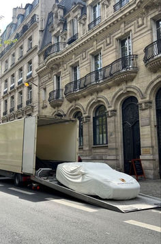 a large truck with a mattress on it's back in front of a building