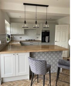 a kitchen with two stools next to a counter top and an island in the middle