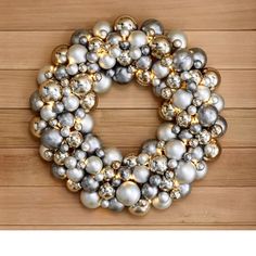 a wreath made out of silver and gold ornaments on a wooden background with space for text