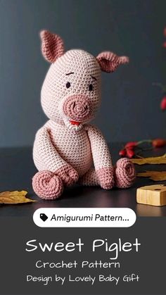 a crocheted pig sitting on top of a table next to a wooden block