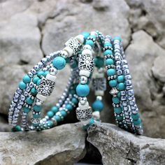 "Fun and festive this seven layer bracelet is sure to make a fresh statement. The turquoise blue and silver beads give that western boho vibe which will compliment nearly all outfits, and is perfect for everyday, beach vacations, or special occasions. The one-size-fits-all feature makes this a great gift for any woman. Made with memory wire, a kind of wire that never loses its shape. You simply wrap the bracelet around your wrist. The bracelet coils wrap around the wrist and gives the impression Bohemian Multi-strand Beaded Bracelets With Silver Beads, Stackable Turquoise Jewelry For Festivals, Turquoise Multi-strand Wrap Bracelet, Turquoise Stackable Bracelets For Festivals, Silver Wrap Bracelet With Colorful Round Beads, Silver Beaded Bohemian Wrap Bracelet, Bohemian Stackable Beaded Bracelets In Turquoise, Stackable Bohemian Turquoise Beaded Bracelets, Bohemian Silver Wrap Bracelet With Colorful Beads