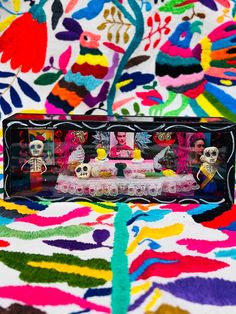 an image of a table setting with sugar skulls on it and colorful fabric in the background