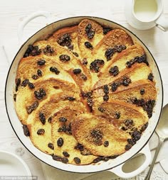 a pan filled with bread and raisins sitting on top of a white table