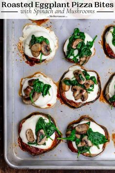 small pizzas with spinach, mushrooms and cheese on a baking sheet