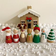 a group of christmas figurines sitting in front of a house with snow on the ground