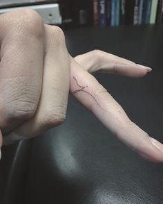 a person's hand with a tiny tattoo on it, holding the finger of another persons hand