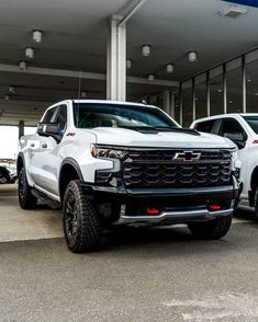 two white trucks parked in front of a building