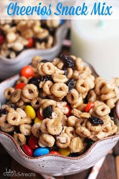 a bowl full of cheerios snack mix next to a glass of milk and candy