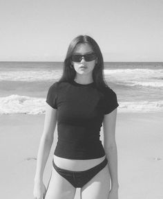 a woman standing on top of a beach next to the ocean