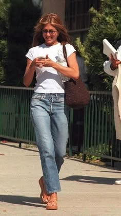 a woman walking down the street while looking at her cell phone