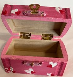 an open pink wooden box with hearts painted on it