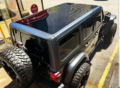 the back end of a black jeep parked in front of a bus stop with its doors open