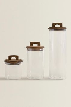 three glass containers with wooden lids and lids