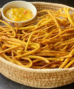 a basket filled with french fries next to a bowl of dipping sauce on the side