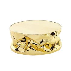 a gold metal container with leaves on the top and bottom, sitting on a white surface