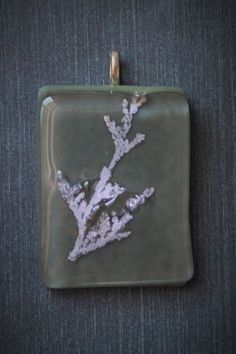 a square glass pendant with a branch on it