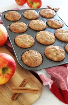 muffins in a pan next to apples and cinnamon sticks