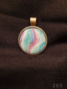 a pendant with a colorful design on it sitting on a brown fabric background and the words, 2013 written in gold lettering