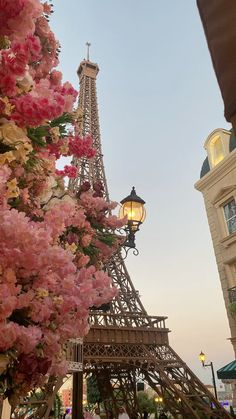 the eiffel tower is surrounded by pink flowers in front of a street light