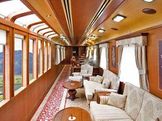 the inside of a train car with couches, tables and chairs on each side