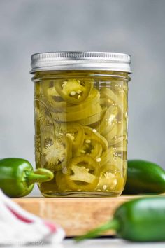 pickled jalapenos in a jar on a cutting board next to peppers