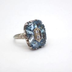 Edwardian era 18k (.750) white gold statement ring, featuring Aquamarine petals with a double Diamond centerpiece. There are 8 Aquamarine stones measuring approx. 5.7 mm x 4.7 mm, two Diamonds are approx. 0.1ctw. The setting is accented with engraved designs corresponding to the named period. This stunning ring is a size 5 3/4, it is 17 mm long, weighing 4.6 grams. EA3791 Diamond Centerpiece, Statement Rings Diamond, March Birthstone Jewelry, Dragon Ring, Double Diamond, Gold Statement Ring, Everyday Rings, Aquamarine Stone, Edwardian Era