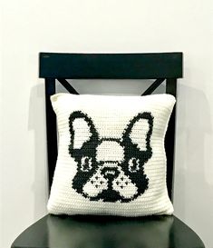 a black chair with a white pillow on it that has a dog's face drawn on it