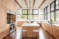 a large kitchen with wooden cabinets and white counter tops, along with two stools in front of the center island