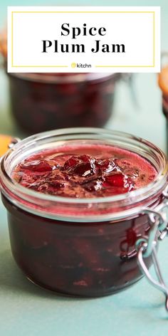 a glass jar filled with plum jam on top of a blue countertop next to sliced oranges