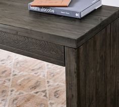 a table with a book on top of it and a rug in front of it