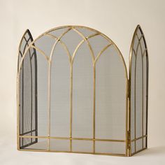 an ornate gold fireplace screen with arched glass panels on the front and sides, set against a plain white background