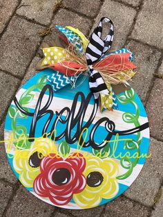 a painted sign with the word hello written on it and an orange, yellow, green, red, blue flower