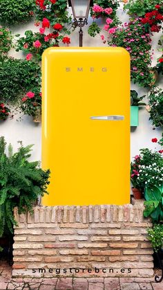 a yellow refrigerator sitting in front of some flowers