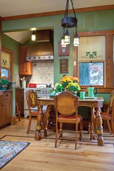 a kitchen with wooden floors and green walls, has an island in the middle that is surrounded by chairs