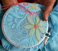 a person is stitching something on a blue piece of cloth