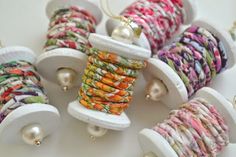 several spools of thread and pearls are on display in white holders with beads