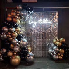 balloons are arranged in the shape of a christmas tree with gold, black and silver balls