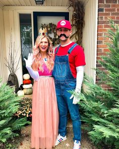 a man and woman dressed up as mario and princess peach are standing in front of a house