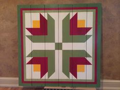 a quilted wall hanging in the corner of a room with wood planks on it