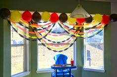 a blue chair sitting in front of a window with balloons hanging from it's sides