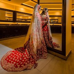 two women in red and gold wedding gowns standing next to each other