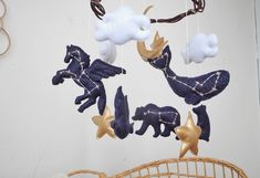 an animal mobile hanging from the ceiling in front of a wall with clouds and stars