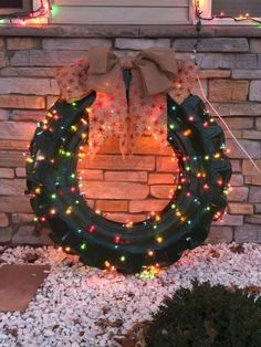 a wreath with christmas lights on it sitting in front of a brick wall and door