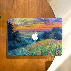 an apple mouse pad sitting on top of a wooden table next to a green plant