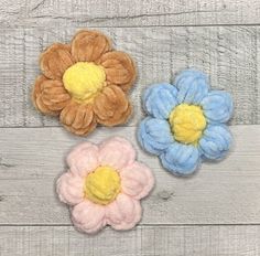 three different colored flowers sitting on top of a wooden table